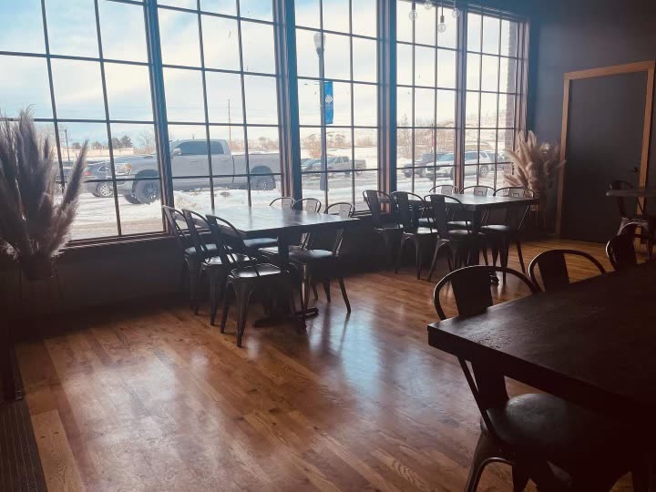 The Bakehouse & Co. dining room: dark wood tables, black metal chairs and tall windows full of winter sunlight
