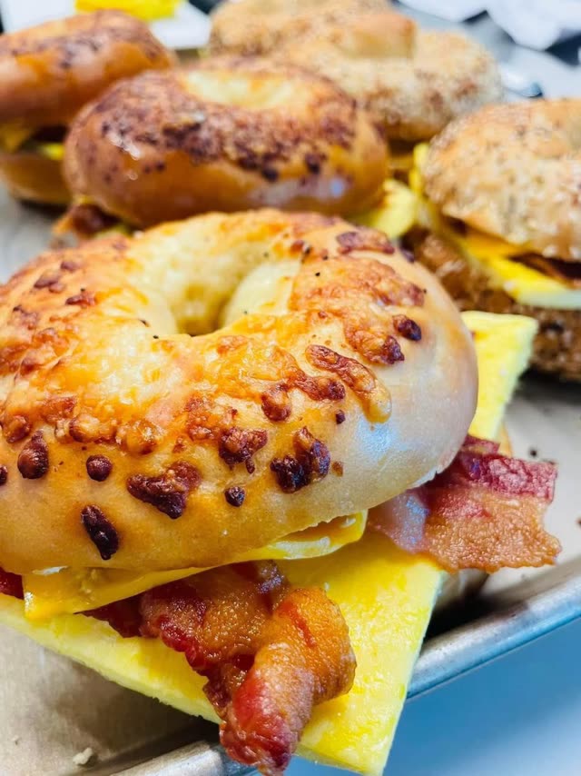 Cheese-toasted bagel breakfast sandwiches stacked with egg and crispy bacon